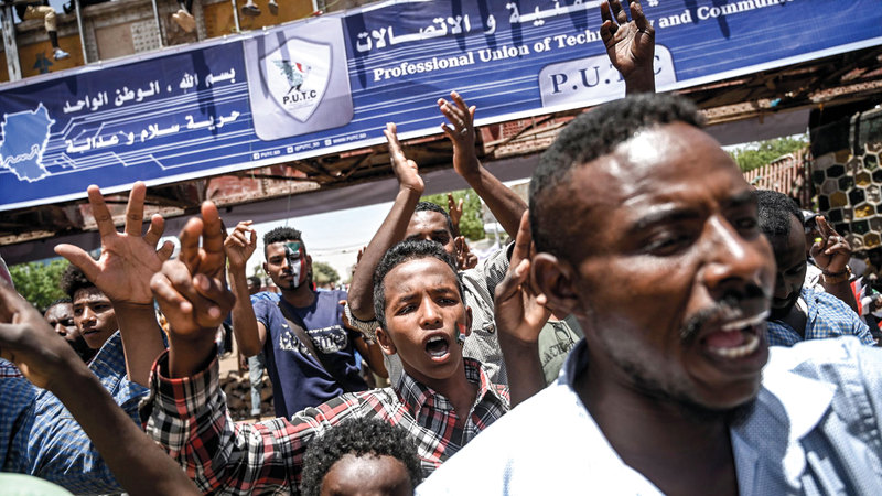 محتجون سودانيون يرفعون شارة النصر بالقرب من مقر قيادة الجيش في الخرطوم. أ.ف.ب