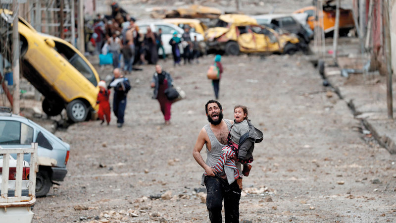 رجل يبكي وهو يحمل ابنته هرباً من جحيم «داعش» في الموصل. أرشيفية