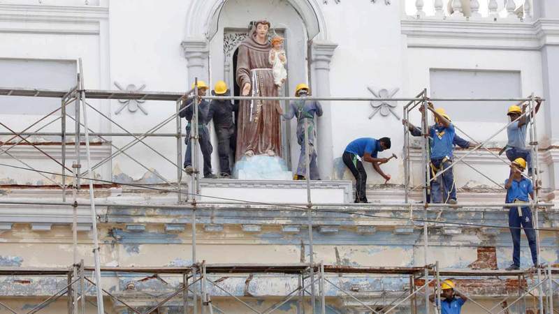 العمال يصلحون الدمار الذي لحق بكنيسة سانت أنطوني في الهجوم الانتحاري.  إي.بي.إيه