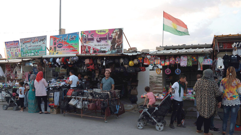 باعة جائلون يعرضون منتجاتهم خارج مخيم للاجئين في دهوك شمال العراق.  أ.ف.ب