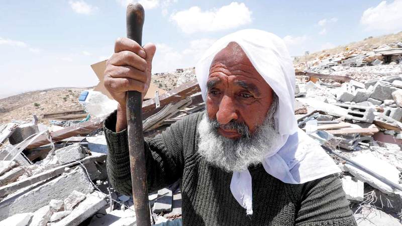 فلسطيني يجلس على حطام منزله الذي دمره الاحتلال في الضفة الغربية بحجة أنه بني دون ترخيص. إي.بي.إيه