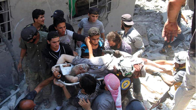 رجال الدفاع المدني ينتشلون الجرحى والقتلى من تحت أنقاض البنايات التي هدمت جراء القصف.  أ.ب