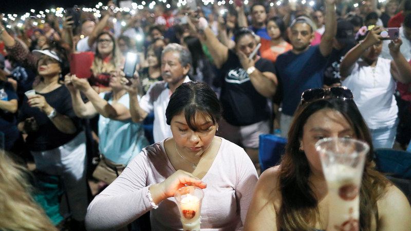 أشخاص يشعلون الشموع حزناً على ضحايا مجزرة إل باسو.  غيتي