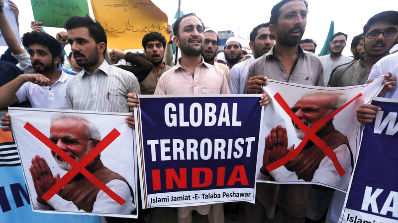 أشخاص يحملون صوراً لمودي احتجاجاً على تغيير حكومته للوضع الخاص بكشمير.  إي.بي.إيه