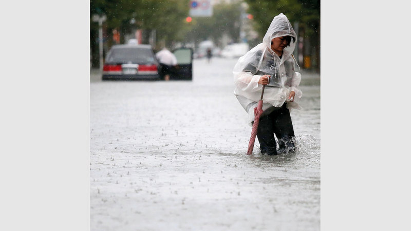 تضع غطاء رأس لوقاية نفسها من مياه المطر.  أ.ف.ب
