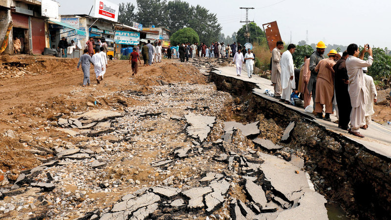 الأهالي يقفون بجوار أحد الطرق التي دمرها الزلزال. رويترز