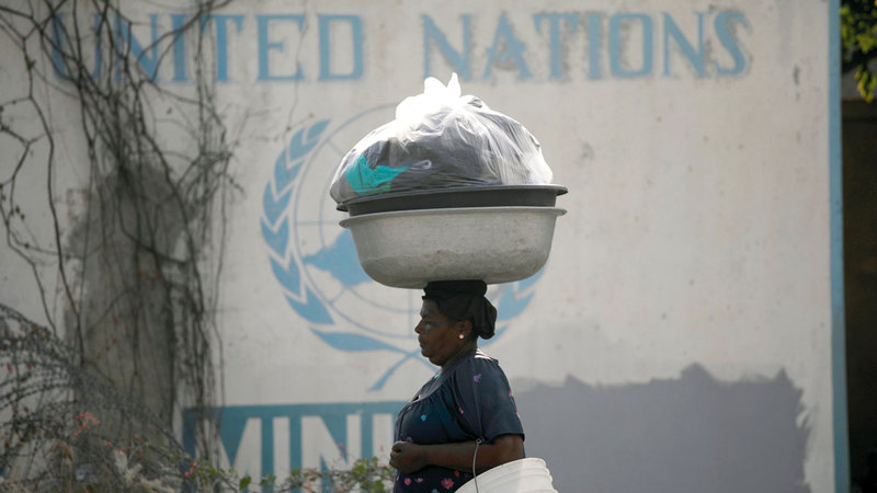 سيدة تحمل أغراضاً لبيعها تمرّ قبالة مقر البعثة الأممية في بورت أو برنس. رويترز