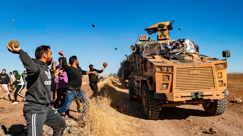 أكراد يرشقون سيارة عسكرية تركية بالحجارة في المنطقة العازلة شمال سورية. أ.ف.ب