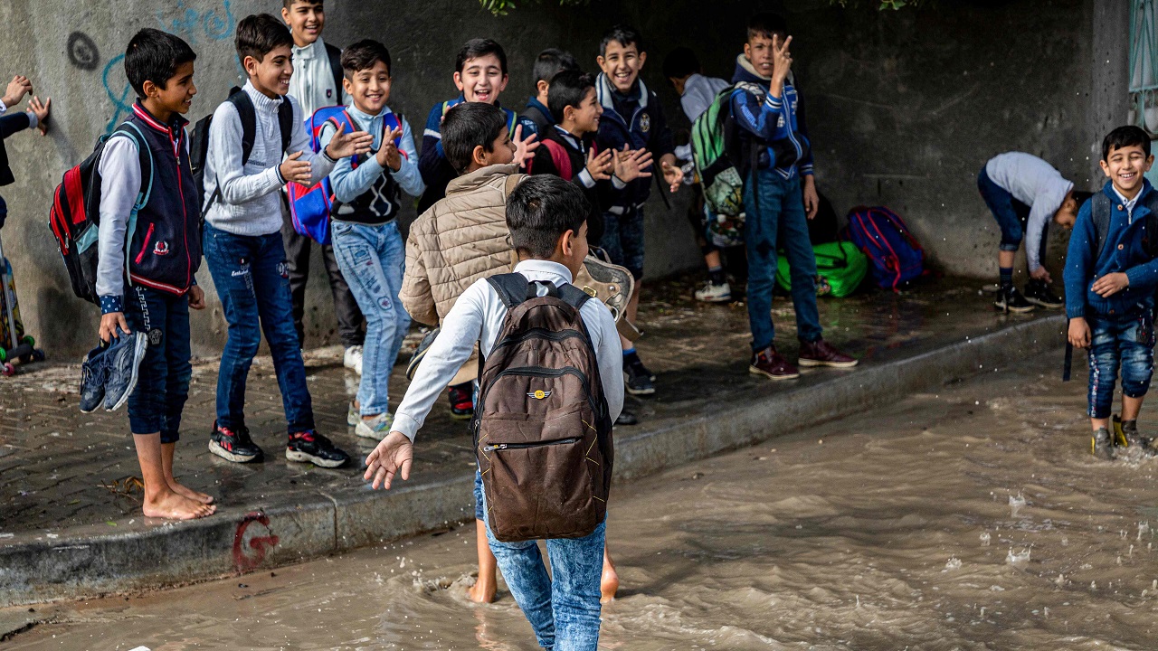 1. الأطفال يلعبون في مياه الأمطار عقب خروجهم من المدرسة (أ. ف. ب)