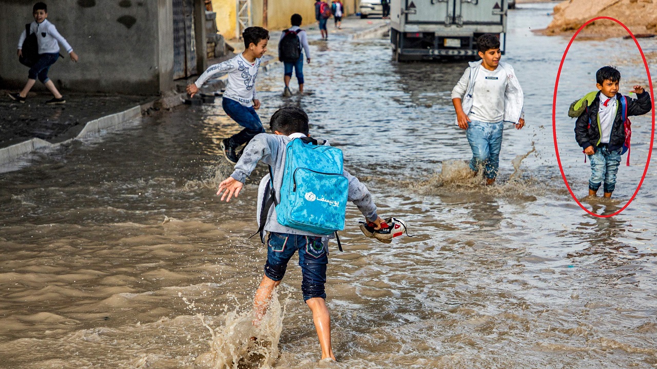 2. طفل يرتدى سترة سوداء يقف وسط المياه (أ. ف. ب)