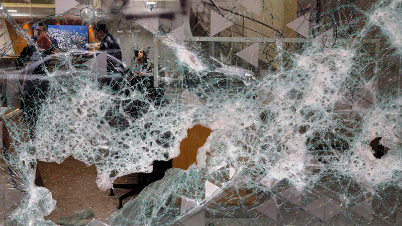 لبنانيون داخل بنك تحطمت واجهته. أ.ب