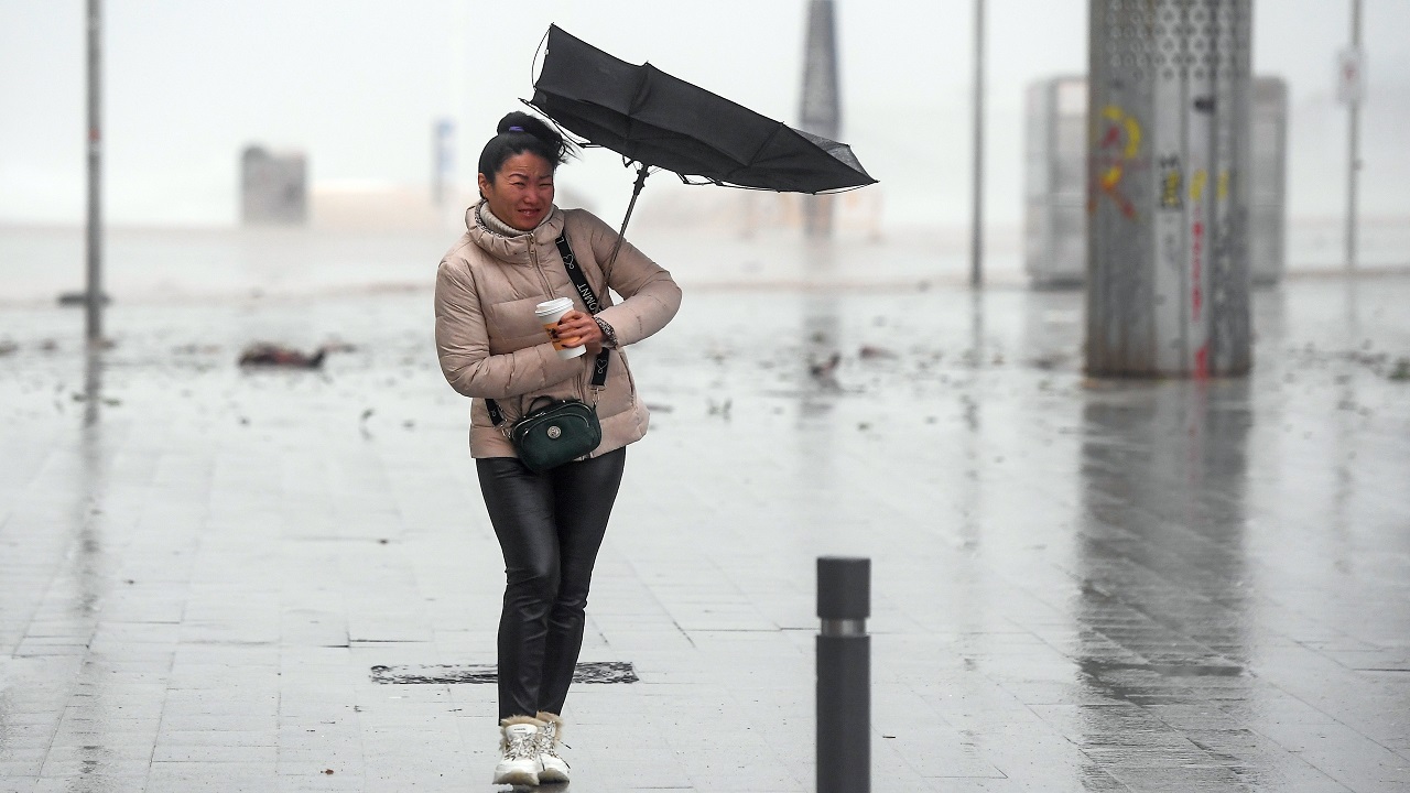 امرأة تمشي بصعوبة بسبب الرياح القوية في برشلونة. (أ. ف. ب)