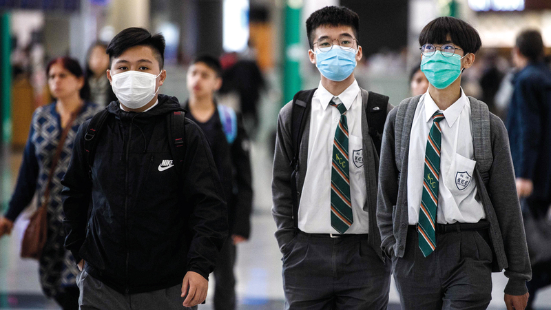 طلاب يضعون الأقنعة في مطار هونغ كونغ الدولي.  أ.ف.ب