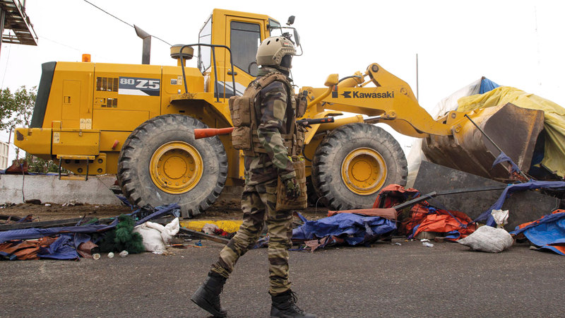 أحد أفراد الأمن بجوار جرار يزيل خيمة اعتصام في البصرة.  أ‌.ف.ب