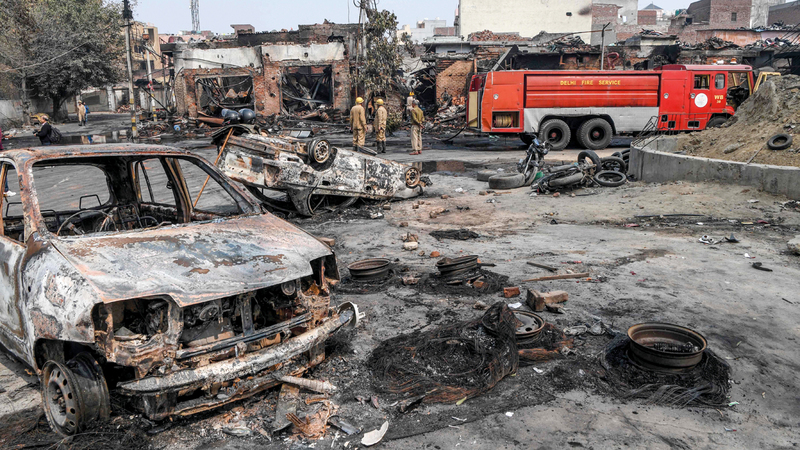 رجال الإطفاء يقفون وسط سوق للإطارات أحرقت بالكامل.  أ.ف.ب