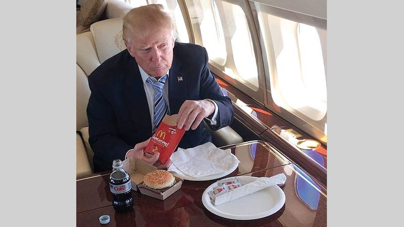 ترامب في طائرته الرئاسية وأمامه أطعمة سريعة.  غيتي