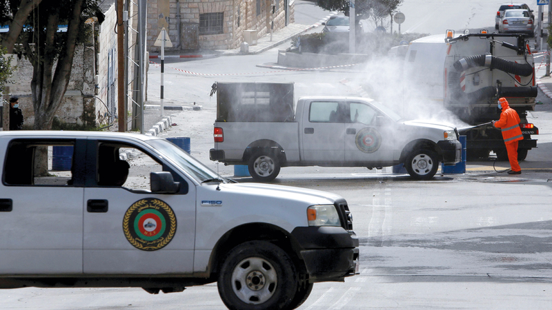 البلدية تطهر مركبات الأمن قرب الحجر الصحي في الضفة الغربية.  أ.ف.ب