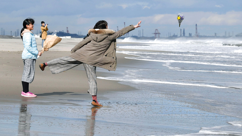 سيدتان تنثران الزهور في مياه البحر ترحماً على ضحايا الزلزال وتسونامي.    أ.ب
