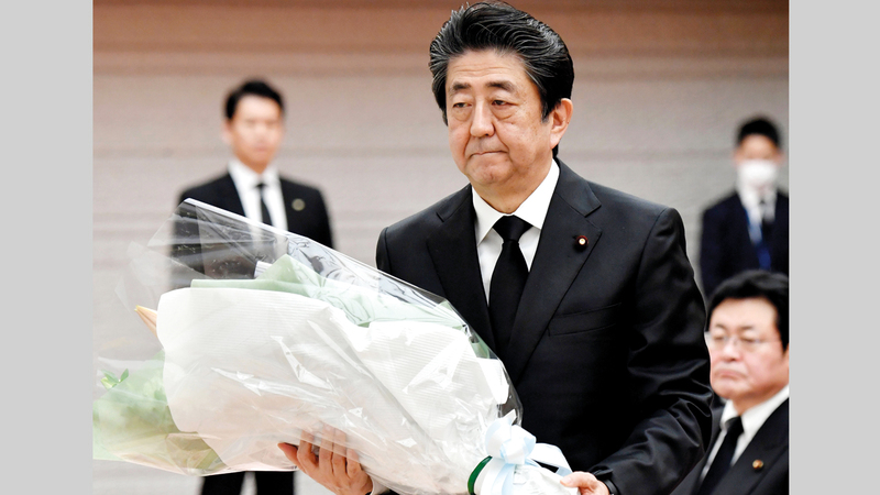 شينزو آبي يضع باقة زهور على نصب شكلي لضحايا تسونامي في مكتبه أمس.   أ.ب