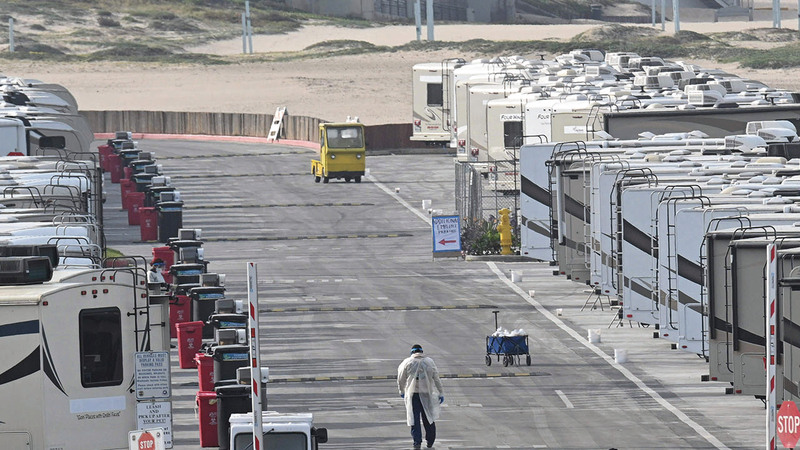 عدد من أفراد الفريق الطبي يتجوّلون وسط بيوت مخيم العزل. أ.ف.ب