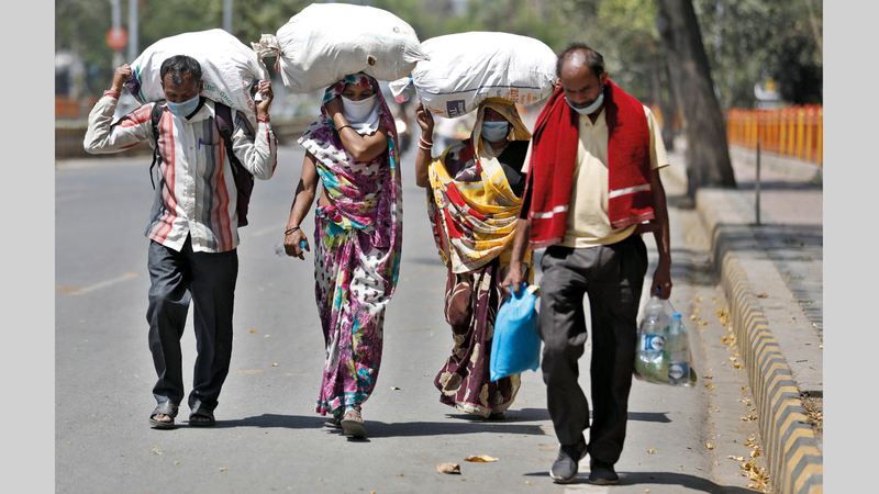 مجموعة من عمال المياومة الهنود يحملون أمتعتهم عائدين إلى قراهم بعد قرار حظر التجوال.أ.ب