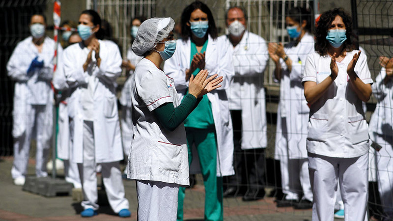 موظفو الرعاية الصحية يصفقون بعد التزامهم دقيقة صمت حداداً على ذكرى ضحايا «كورونا» أمام مستشفى لا برينسيسا في مدريد.  أ.ف.ب