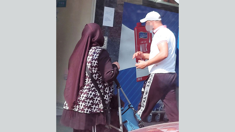 متسولة تحاول استعطاف أحد المستهلكين أمام مركز تجاري. الإمارات اليوم