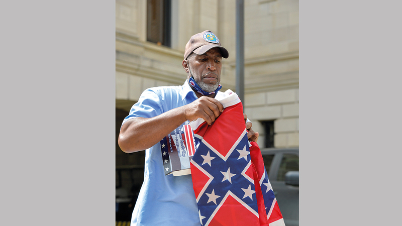 موظف يطوي العلم بعد إنزاله من على ساريته في مبنى كونغرس ولاية مسيسيبي. رويترز