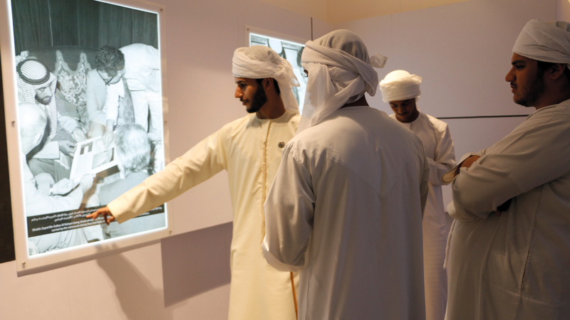 شباب من الإمارات يشاهدون صورة للشيخ زايد خلال استقباله وفداً من وكالة الفضاء الأميركية. «الأرشيف الوطني»