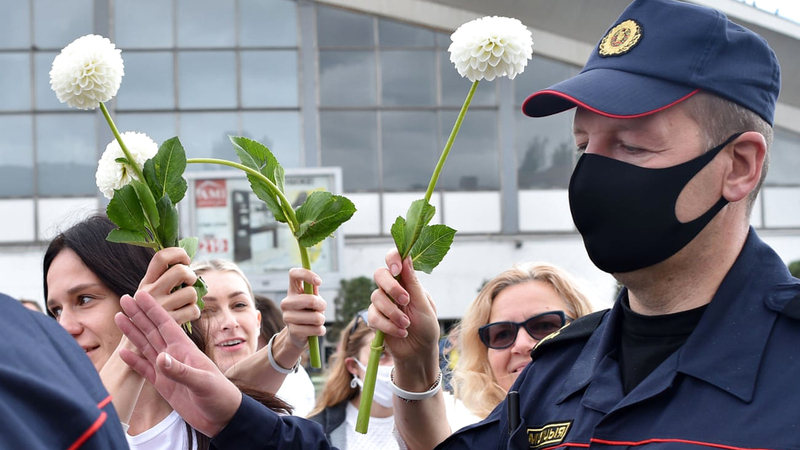 نساء يقدمن الزهور لأحد ضباط الشرطة. من المصدر