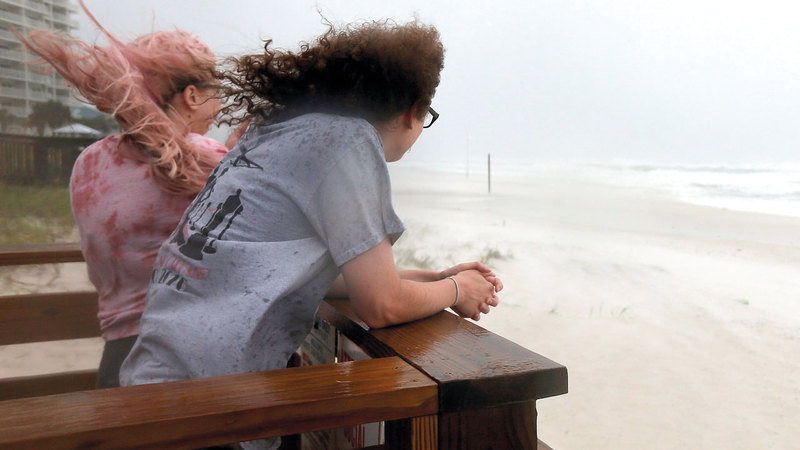 سيدتان تراقبان مياه الشاطئ التي ارتفع منسوبها حتى اقترب من شرفة منزلهما في أورانج بيتش بولاية ألاباما. رويترز