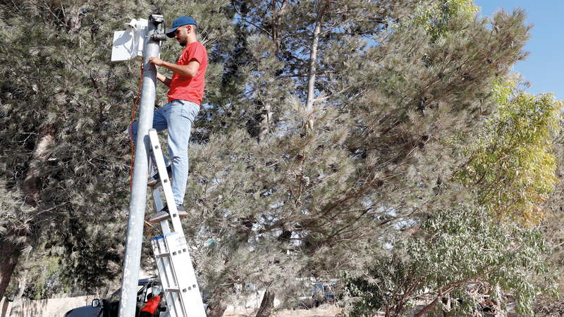 عامل يثبت كاميرا فيديو للمراقبة فوق عمود لتوثيق هجمات المستوطنين.  رويترز