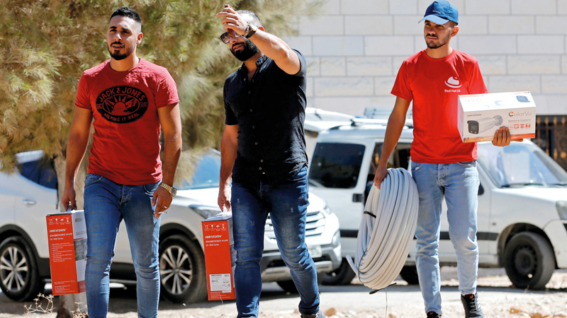 عمال يتابعون تثبيت الكاميرات في أكثر من موقع بقرية كيسان.  رويترز