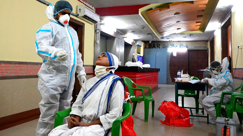 ممرض هندي يجري اختبار مسحة على راهبة في عيادة متنقلة لاختبار «كورونا» في كولكاتا.  أ.ف.ب