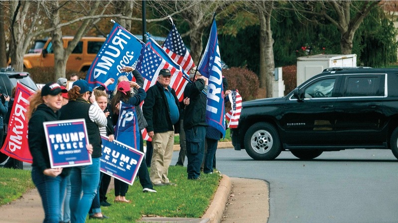 أنصار ترامب يلوحون بالأعلام بينما تدخل سيارته إلى ناديه للغولف في فرجينيا.   أ.ف.ب