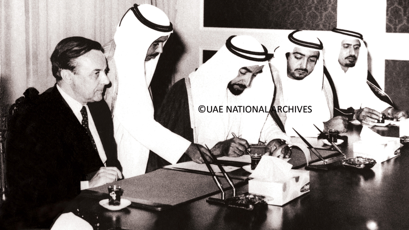 الشيخ زايد بن سلطان آل نهيان، يوقّع على الوثيقة المتعلقة بإنهاء اتفاقية العلاقات الخاصة المبرمة ما بين أبوظبي وبريطانيا، بحضور الشيخ خليفة بن زايد آل نهيان، وأحمد بن خليفة السويدي، ومحمد الحبروش - الأول من ديسمبر 1971.                                       ■ «الأرشيف الوطني»