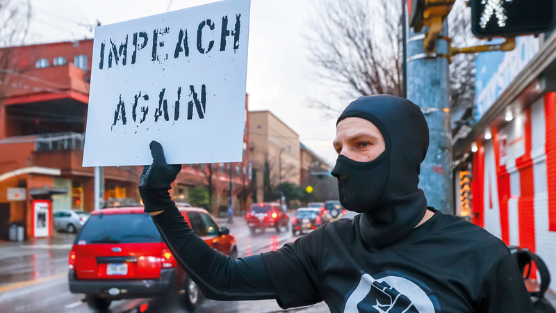 أحد المتظاهرين على سلوك ترامب يرفع لافتة تنادي بمساءلته مرة أخرى وعزله.إي.بي.إيه