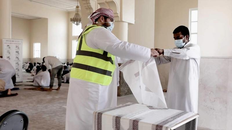 متطوعون يوزعون سجادات صلاة بلاستيكية على المصلين. من المصدر