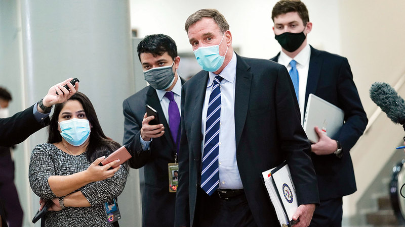 السيناتور الديمقراطي مارك وارنر، يتبعه الصحافيون أثناء سيره في مبنى الكابيتول، بعد انتهاء اليوم الثالث من محاكمة ترامب.  أ.ب