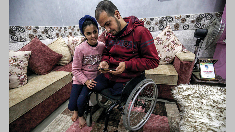 محمد أبوجزر يعرض على ابنته (ميسم) صور أطفاله الذين استشهدوا في حرب 2014 على غزة.   أ.ف.ب