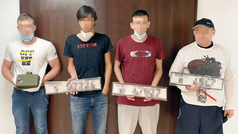 أفراد العصابة بعد القبض عليهم يحملون اللوحات المزورة.  من المصدر