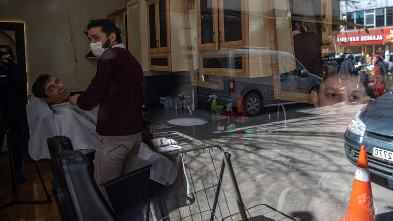 محمد أبوالنار صاحب محل حلاقة يحلم بالعودة إلى بلاده.  أ.ف.ب