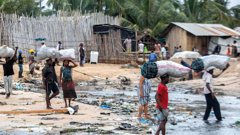 مواطنون يحملون أكياساً معبأة بالكربون لرصها على شواطئ باكوتيكيت انتظاراً لوصول القوارب المحملة بالهاربين من جرائم «داعش».  أ.ف.ب