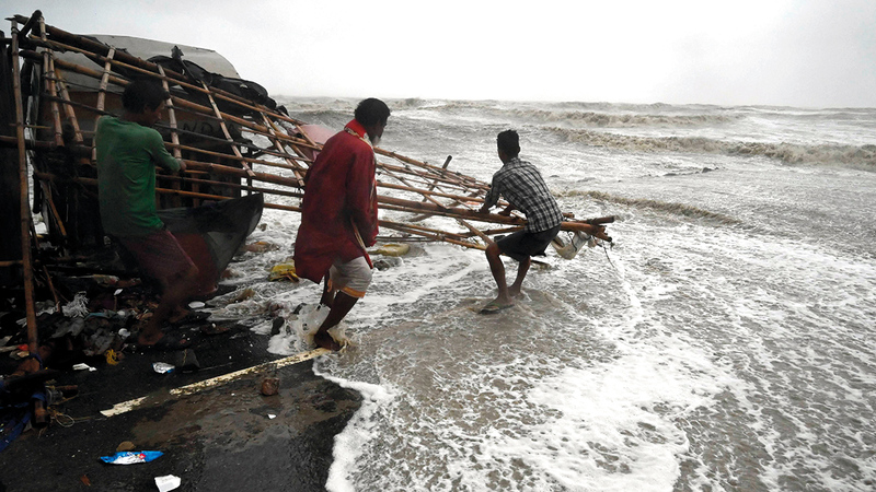 مواطنان هنديان يحاولان إنقاذ ما تبقى لهما من ممتلكات. 	  أ.ف.ب