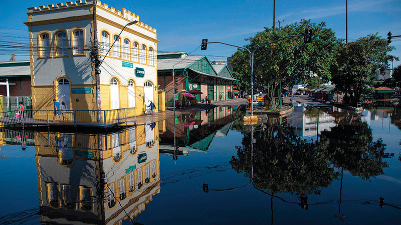 الناس يسيرون فوق ممرات مؤقتة أقيمت في الشوارع تفادياً لمياه الفيضان.  أ.ف.ب
