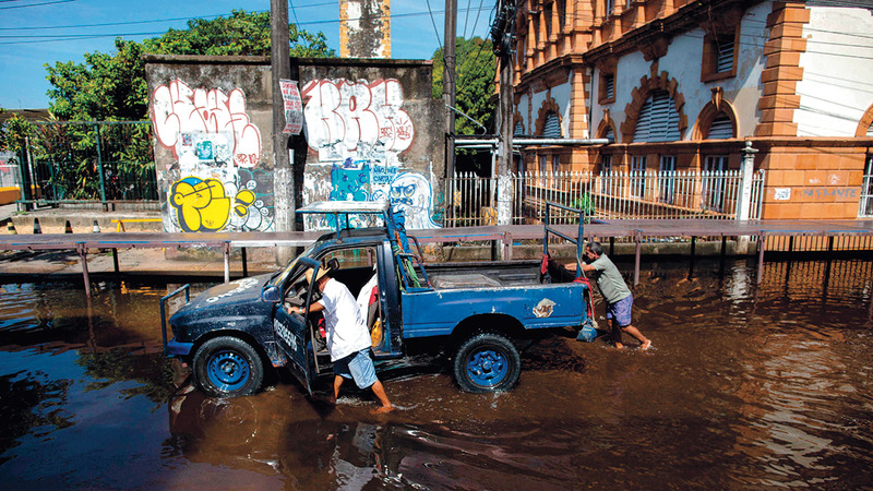 تعطلت سيارته وسط المياه.   أ.ف.ب