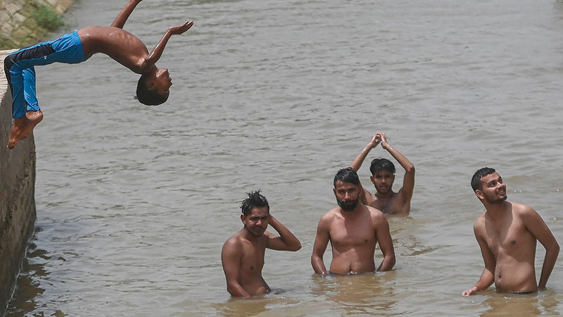 أطفال يطفئون الحرارة الشديدة بالاستحمام في إحدى القنوات بسري جانجانجار شمال الهند.   أ.ف.ب