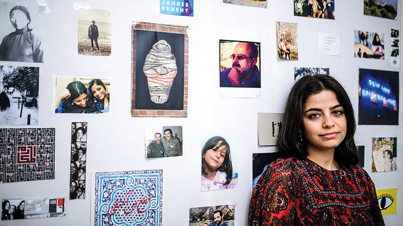 «وفاء» أمام لوحة تعرض صور عائلتها.  من المصدر