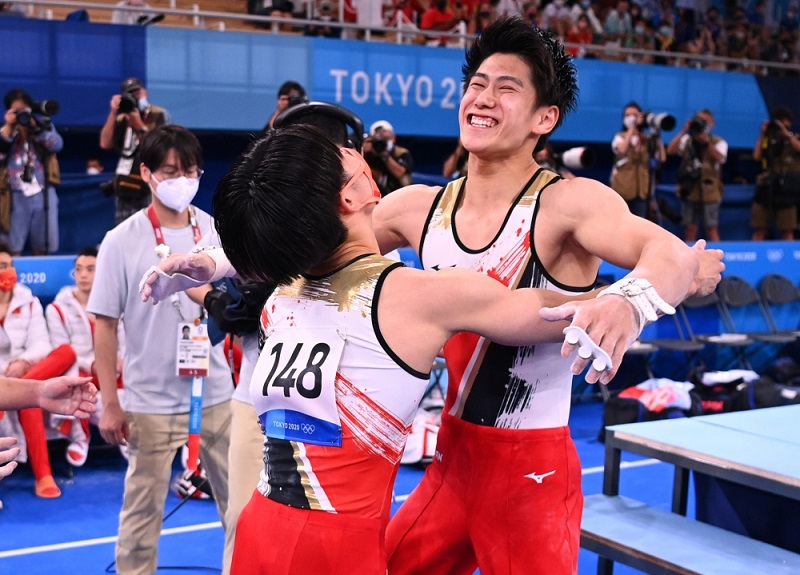 يحتفل الياباني دايكي هاشيموتو مع كازوما كايا الياباني بعد أدائه على العارضة الأفقية ضمن  فريق الرجال في الجمباز.