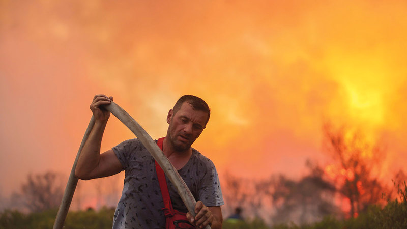 رجل إطفاء متطوع يحمل خرطوم مياه أثناء مكافحة النيران في فاربوبي.  رويترز